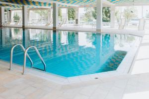 a swimming pool with blue water in a building at HEIMATEL - Suiten, Apartments und Studios in Scheidegg