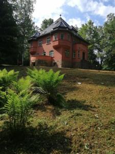 a large red brick house on a hill with trees at Baltic Home in Polanica-Zdrój