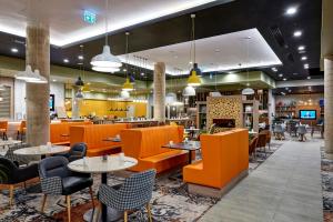 a restaurant with orange chairs and tables and a bar at Holiday Inn Manchester - City Centre by IHG in Manchester