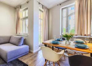 a dining room with a table and chairs and a couch at Imperial Apartments - Monte Deluxe in Sopot