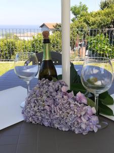 a table with two wine glasses and purple flowers at Il Limoneto di Leo in Mascali