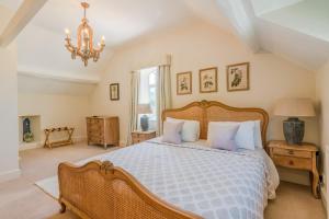 a bedroom with a large bed and a chandelier at Colebrook Cottage in Blockley