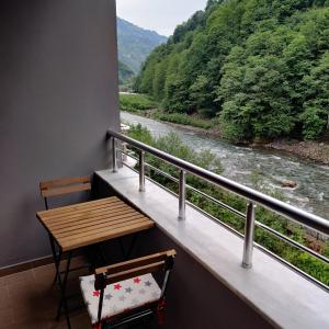 een balkon met een tafel en uitzicht op een rivier bij Elegant Residence in Çamlıhemşin