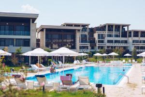a swimming pool with chairs and umbrellas in front of a building at Apolonia Resort in Sozopol
