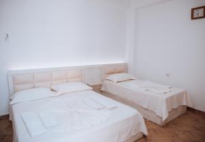 two beds in a room with white walls at Hotel Perdja in Velipojë