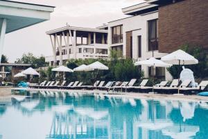 a swimming pool with chairs and umbrellas and a building at Apolonia Resort in Sozopol +84 photos
