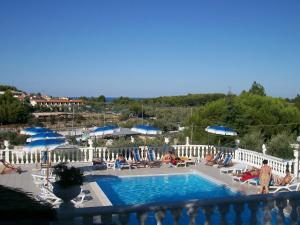 a pool with people sitting in chairs and umbrellas at Althea Village Residence in Vieste