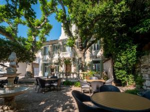 a courtyard with tables and chairs in front of a building at Altera Roma Hôtel in Avignon