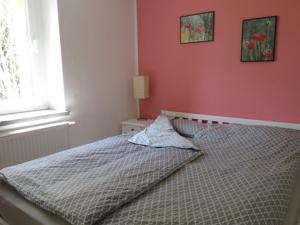 ein Bett in einem Schlafzimmer mit einer rosa Wand in der Unterkunft Blota Kral in Lübben