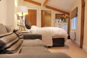 ein Schlafzimmer mit einem Bett, einem Sofa und einer Lampe in der Unterkunft Croft House Guest Suite Painswick in Painswick