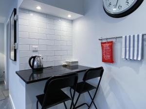 a counter with two chairs and a clock on a wall at THE STUDIO MAIDENHEAD RIVERSIDE in Maidenhead