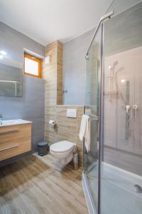 a bathroom with a toilet and a glass shower at Holiday Hotel Siófok in Siófok