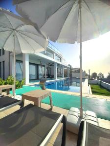 a pool with two umbrellas and chairs and a house at Villa Rosy Sunset in Fethiye