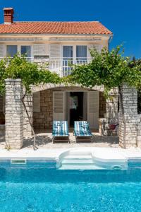 a house with two chairs next to a swimming pool at Villa Gradina 01 in Vela Luka