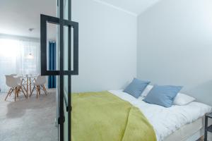 Schlafzimmer mit einem Bett mit blauen Kissen und einem Tisch in der Unterkunft Resort Apartamenty Klifowa Rewal 59 in Rewal