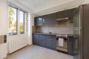 een keuken met blauwe kasten en een roestvrijstalen koelkast bij Travel Homes - L'Alsacien, près de la ville in Mulhouse