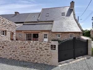 a brick house with a gate and a stone wall at L'Tas De Cailloux in Cancale