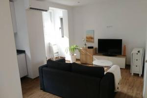 un salon avec un canapé noir et une télévision dans l'établissement Xativa, Style Apartment, à Xàtiva