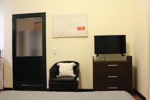 1 dormitorio con TV, silla y vestidor en Quarto vista mar, en Câmara de Lobos
