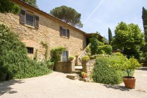 une ancienne maison en pierre avec un portail et des buissons dans l'établissement Villa Ugo, à Cortone