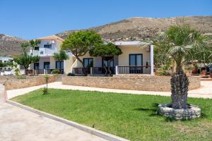 a house with a palm tree in the grass at Adam in Falasarna