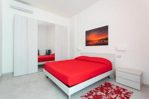 CASA L'ANGOLO FIORITO في كابراس: غرفة نوم بيضاء بسرير احمر وسجادة حمراء