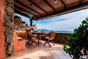 un patio con mesa, sillas y pared de piedra. en Alma Del Mar Porto Rotondo en Porto Rotondo