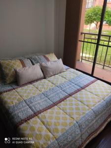 a bed with a quilt on it in front of a window at Apartamento en Mosquera in Mosquera