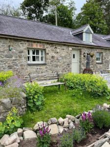 una casa de piedra con un banco delante en Crug Yr Eryr Isaf en Llandysul