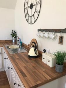 a kitchen with a wooden counter top with a clock on the wall at Little Banks Barn in Ringwood