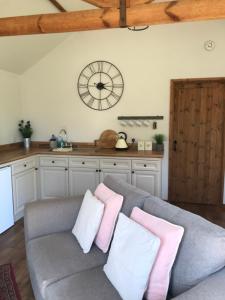 a living room with a couch and a clock on the wall at Little Banks Barn in Ringwood