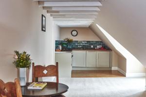 uma cozinha com armários brancos, uma mesa e uma escada em Brambles of Inveraray em Inveraray