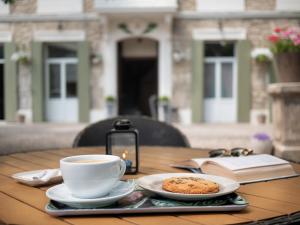 a table with a cup of coffee and a book at Altera Roma Hôtel in Avignon