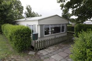 una pequeña casa con una valla y una ventana en CHALET AAN HET STRAND, en Nieuwvliet 14 fotos más