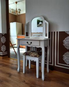 - une coiffeuse blanche avec un miroir et un tabouret dans l'établissement Arāja apartamenti, à Kuldīga