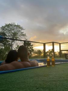 un hombre y una mujer sentados en una piscina viendo la puesta de sol en Massalli Sanctuary Lodge, en San Andrés