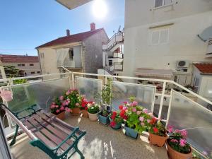 un balcón con un banco y macetas. en Apartman Ninsky en Primošten