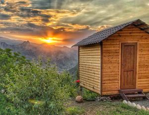 Cabaña de madera con puesta de sol en el fondo en ARMBEE Honey Farm en Alaverdi