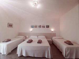 two beds in a room with white walls at B&B EDEN OGLIASTRA in Tortolì