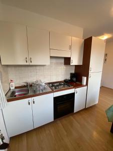 kuchnia z białymi szafkami, zlewem i kuchenką w obiekcie Varga apartment w mieście Opatija