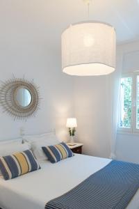 1 dormitorio con cama blanca y espejo en NEFELI'S GUESTHOUSE IN PLATYS GIALOS SIFNOS, en Platis Yialos Sifnos