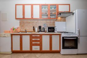 een keuken met witte apparaten en houten kasten bij Apartments Šćerbe 3103 in Rab