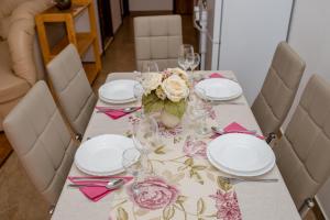 een tafel met borden, glazen en bloemen erop bij Apartments Šćerbe 3103 in Rab