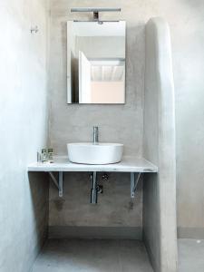 een witte wastafel in een badkamer met een spiegel bij Fabrica Sunset Apartments in Megali Ammos