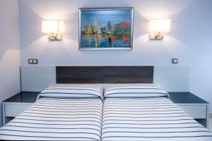 a bedroom with a bed with two lights on the wall at Pensión Plaza in Santander