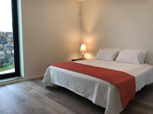 a bedroom with a large bed with a red blanket at Jubileu 74 in Caloura