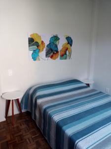 - une chambre avec un lit doté d'une couverture bleue et d'une table dans l'établissement Apartamento 3 Qts Superconfortavel em Itapoã., à Vila Velha