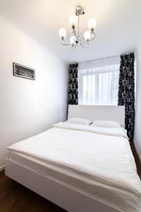 リヴィウにあるLEOGRAND Apartments on Svobodyのベッドルーム1室(白いベッド1台、シャンデリア付)