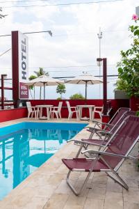 uma piscina com cadeiras, mesas e guarda-sóis em Mira Maré Praia Hotel no Guarujá