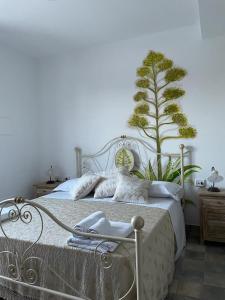 ein Schlafzimmer mit einem Bett mit einer Pflanze an der Wand in der Unterkunft Bàcula Nzícula Marzamemi in Marzamemi